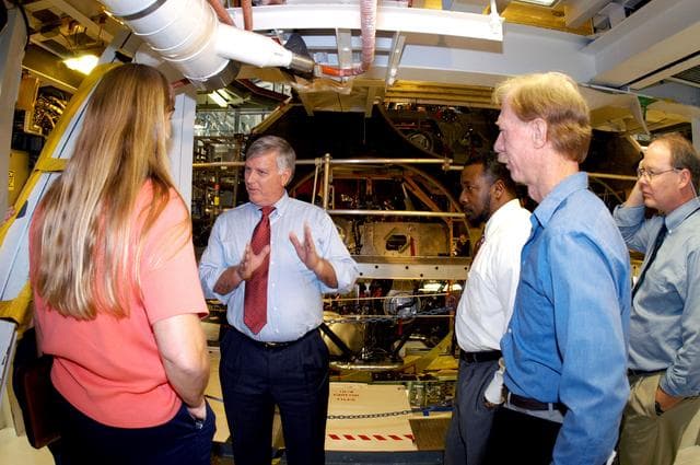 NASA image: KENNEDY SPACE CENTER, FLA. - On a tour of the Orbiter Processing Facility, Center Director Jim Kennedy and Deputy Director Woodrow Whitlow Jr.  (center, left and right) talk with Kathy Laufenberg, Orbiter Airframe Engineering ground rea manager,  and Tom Roberts, Airframe Engineering System specialist, both with United Space Alliance. At far right is Bruce Buckingham, assistant to Dr. Whitlow.  They are standing in front of the aft base heatshield of Endeavour, which is in its Orbiter Major Modification period that began in December 2003.