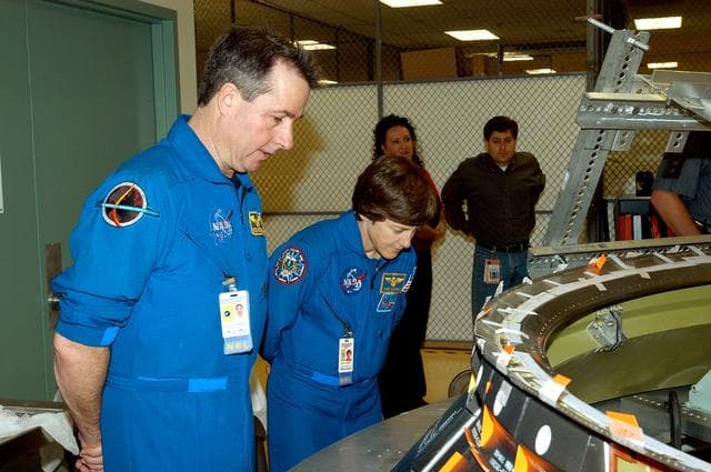 NASA image: KENNEDY SPACE CENTER, FLA. -  Members of the STS-114 crew spend time in the Orbiter Processing Facility becoming familiar with Shuttle and mission equipment.  Mission Specialists Stephen Robinson (left) and Wendy Lawrence (right) look at an engine eyelet, which serves as part of the thermal protection system on an orbiter.  The STS-114 mission is Logistics Flight 1, which is scheduled to deliver supplies and equipment and the external stowage platform to the International Space Station.