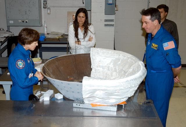 NASA image: KENNEDY SPACE CENTER, FLA. - STS-114 Mission Specialists Wendy Lawrence (left) and Stephen Robinson (right) look at the insert for Discovery’s nose cap that is being fitted with thermal protection system insulation blankets.  The mission crew is spending time becoming familiar with Shuttle and mission equipment.  The mission is Logistics Flight 1, which is scheduled to deliver supplies and equipment plus the external stowage platform to the International Space Station.