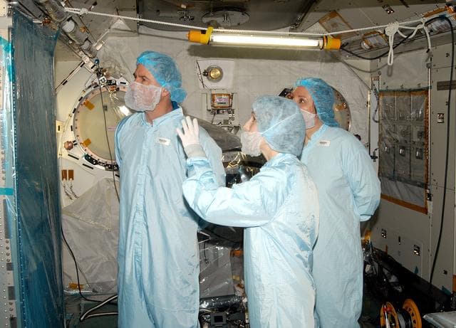 NASA image: KENNEDY SPACE CENTER, FLA. - - In the Space Station Processing Facility, STS-114 Mission Specialist Stephen Robinson (left) learns about the Japanese Experiment Module (JEM) from Jennifer Goldsmith (center), with United Space Alliance at Johnson Space Center, and Louise Kleba (right), with USA at KSC.  Crew members are at KSC to become familiar with Shuttle and mission equipment. The mission is Logistics Flight 1, which is scheduled to deliver supplies and equipment plus the external stowage platform to the International Space Station.