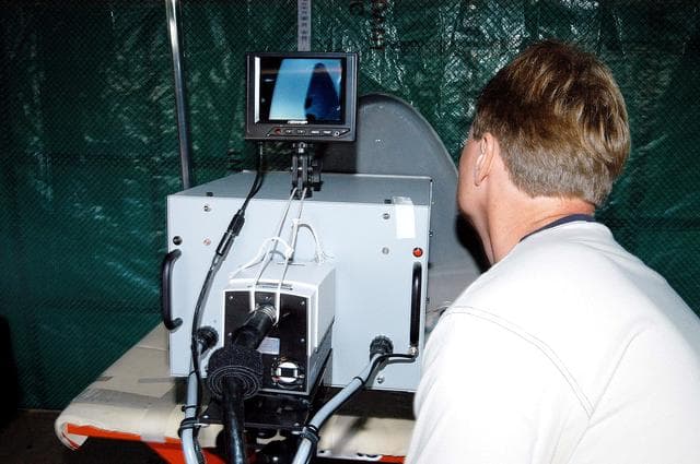 NASA image: KENNEDY SPACE CENTER, FLA. -  Jim Landy, NDE specialist with United Space Alliance (USA), prepares equipment to examine a Reinforced Carbon Carbon panel using flash thermography.  A relatively new procedure at KSC, thermography uses high intensity light to heat areas of the panels. The panels are then immediately scanned with an infrared camera. As the panels cool, any internal flaws are revealed. The gray carbon composite RCC panels are attached to the leading edge of the wing of the orbiters.  They have sufficient strength to withstand the aerodynamic forces experienced during launch and reentry, which can reach as high as 800 pounds per square foot.  The operating range of RCC is from minus 250º F to about 3,000º F, the temperature produced by friction with the atmosphere during reentry. The panels will be installed on the orbiter Discovery, designated for the first Return to Flight mission, STS-114.
