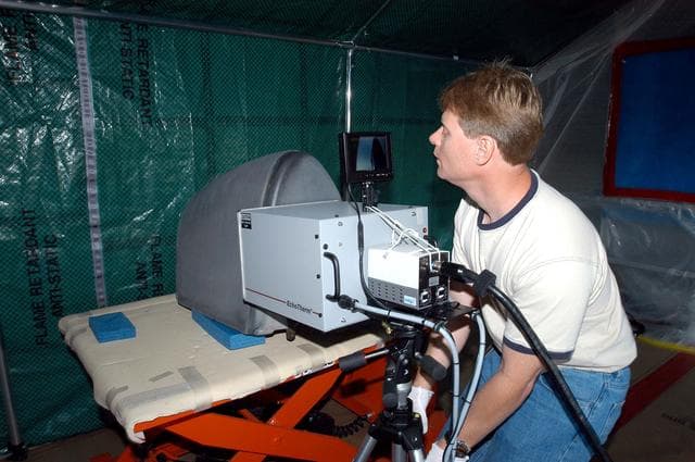 NASA image: KENNEDY SPACE CENTER, FLA. -  Jim Landy, NDE specialist with United Space Alliance (USA), examines a Reinforced Carbon Carbon panel using flash thermography.  A relatively new procedure at KSC, thermography uses high intensity light to heat areas of the panels. The panels are then immediately scanned with an infrared camera. As the panels cool, any internal flaws are revealed. The gray carbon composite RCC panels are attached to the leading edge of the wing of the orbiters.  They have sufficient strength to withstand the aerodynamic forces experienced during launch and reentry, which can reach as high as 800 pounds per square foot.  The operating range of RCC is from minus 250º F to about 3,000º F, the temperature produced by friction with the atmosphere during reentry.  The panels will be installed on the orbiter Discovery, designated for the first Return to Flight mission, STS-114.