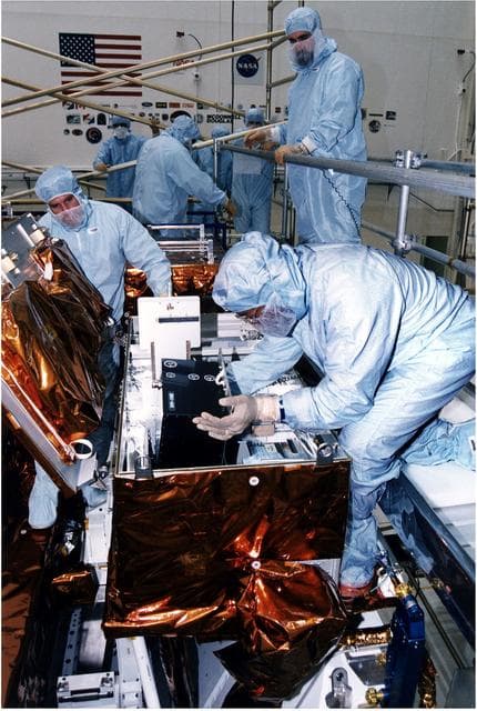 NASA image: KENNEDY SPACE CENTER, FLA. -  Workers in KSC's Vertical Processing Facility install a solid state recorder into a transport assembly in its protective enclosure as part of the prelaunch preparations for STS-82, the second Hubble Space Telescope servicing mission.  The digital solid state recorder will replace one of three engineering/science tape recorders on Hubble.  The solid state recorder has no moving parts to wear out.  It also is more flexible than a reel-to-reel recorder and can store 10 times as much data.  Liftoff aboard Discovery is targeted Feb. 11 with a crew of seven.
