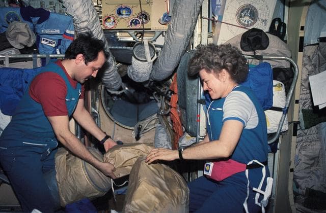 NASA image: Mir 21 crew and Astronaut Lucid stowing equipment