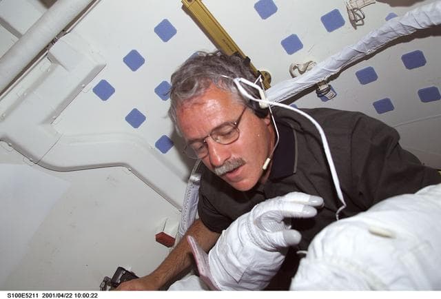 NASA image: MS Phillips helps a fellow crewmember with his EMU before the first EVA of STS-100
