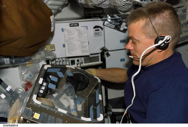 NASA image: McCool works with Leukin activator cartridges on Columbia's MDK during STS-107