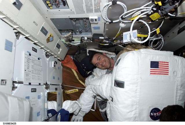 NASA image: STS-109 PLT Carey helps prepares for EVA 4 on middeck