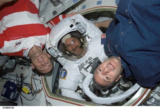 NASA image: MS Grunsfeld wearing EMU in Airlock joined by MS Newman and Massimino