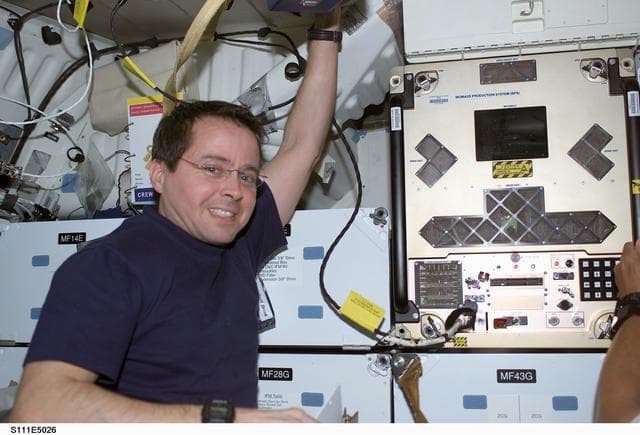 NASA image: Bursch poses next to BPS installed in a slot on Endeavour's middeck for return on STS-111 UF-2