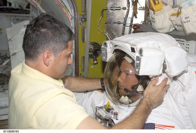 NASA image: EVA Prep OPS - PLT Lockhart assists MS Lopez-Alegria with EMU Helmet during STS-113
