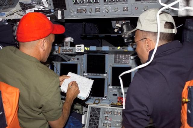 NASA image: Sturckow and Archambault look over checklists on the FD of STS-117 Space Shuttle Atlantis