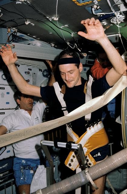 STS-32 crewmembers hold finish line banner as MS Low races on treadmill