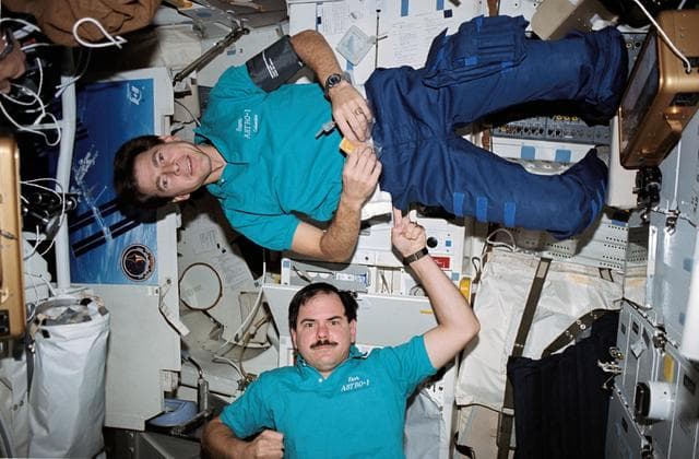 NASA image: STS-35 payload specialists perform balancing act on OV-102's middeck