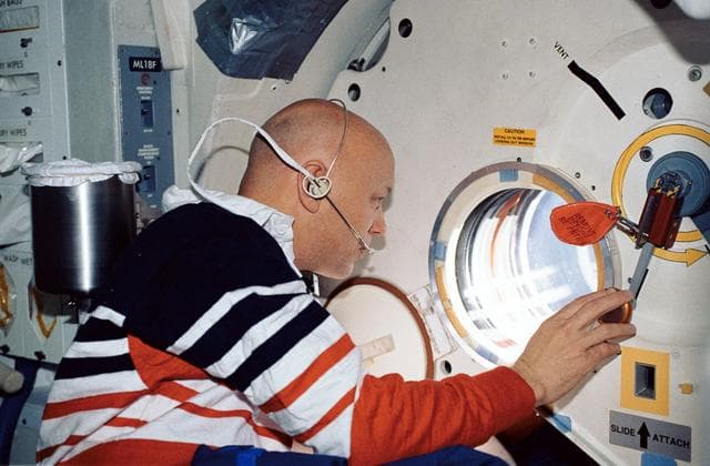 NASA image: STS-44 MS Musgrave looks out OV-104's side hatch viewport on middeck