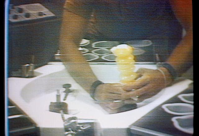 NASA image: Skylab beverage container filled with orange juice held by Astronaut Conrad
