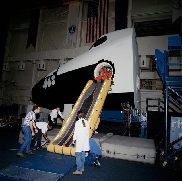 NASA image: STS-73 using the escape slide in bldg 9A