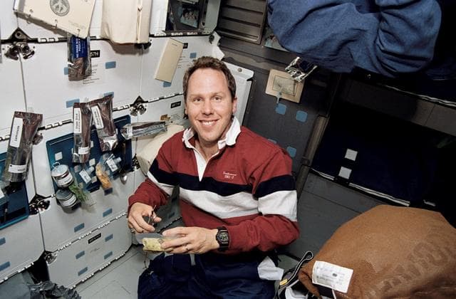 NASA image: Astronaut Thomas Jones opens food package on middeck