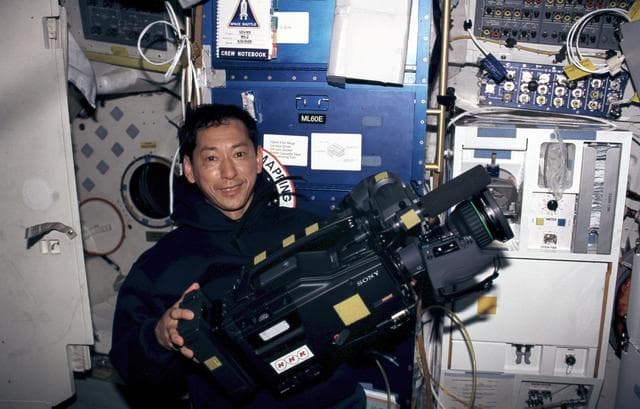 NASA image: STS-99 MS Mohri poses with an HD camera on OV-105's middeck