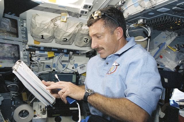 NASA image: MS Burbank reads a checklist on the flight deck during STS-106