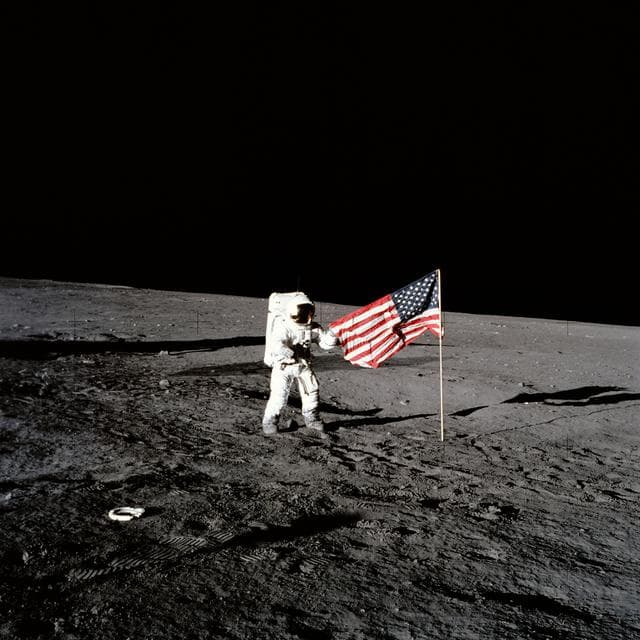 NASA image: Apollo 12 astronaut stands beside United States flag after is was unfurled