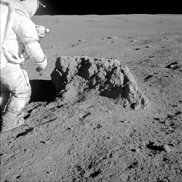 NASA image: Astronaut Alan Shepard stands beside large boulder found by Apollo 14 crew