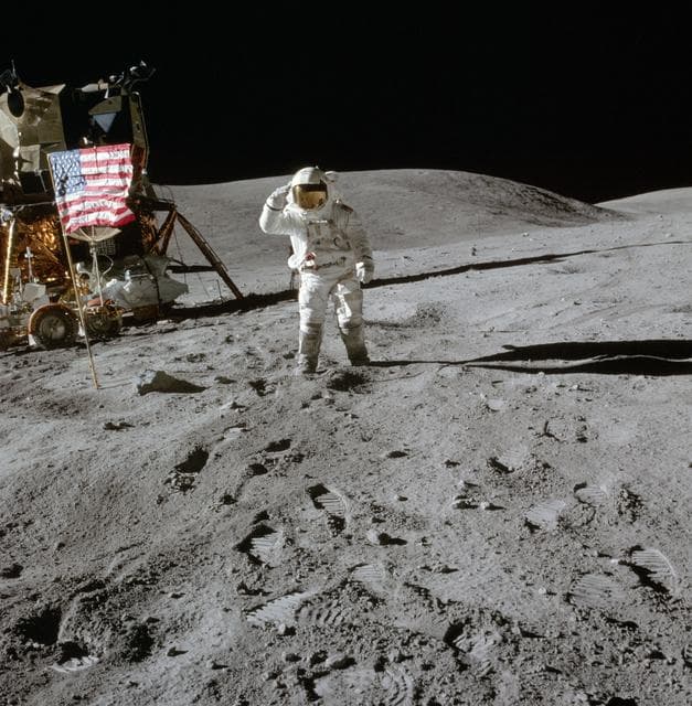 NASA image: Apollo 16 Mission image - View of Station Lunar Module (LM) and Lunar Module Pilot (LMP), Charles M. Duke, Jr., and Flag