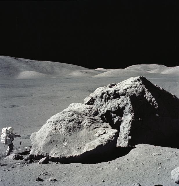 Astronaut Harrison Schmitt standing next to boulder during third EVA
