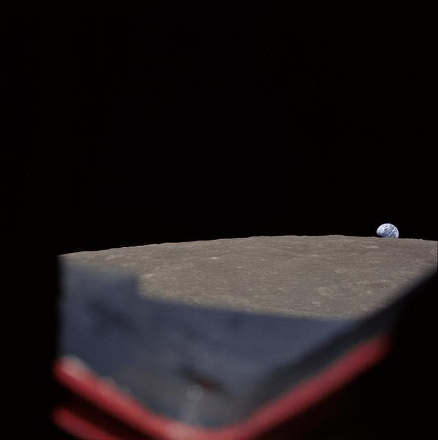 NASA image: High-oblique view of Moon's surface showing earth rising above horizon
