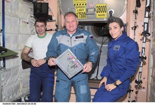 NASA image: The Soyuz Taxi crew pose with the ISS ship log in Node 1 during Expedition Three