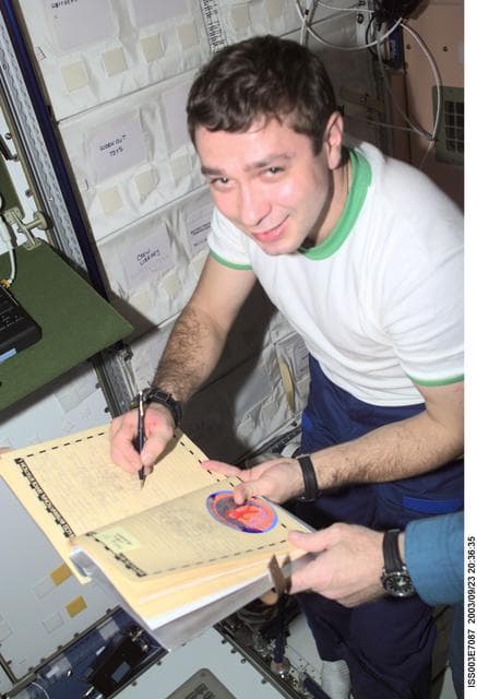 NASA image: Kozeev signs the ISS ship log in Node 1 during the Taxi crew's visit to the ISS