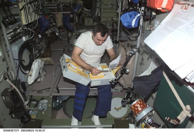 NASA image: Dezhurov looks through a stowage container in Zvezda during Expedition Three