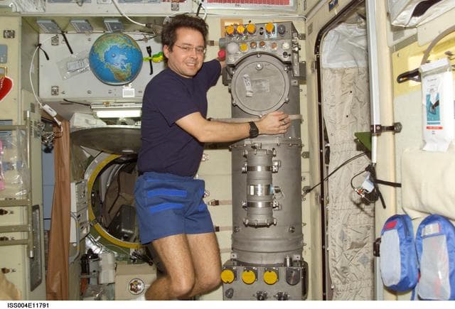 NASA image: Bursch poses next to the Elektron oxygen generator in the SM during Expedition Four