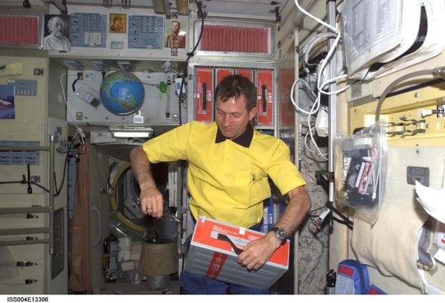 NASA image: Treschev opens a beverage box in the SM during Expedition Four / Expedition Five