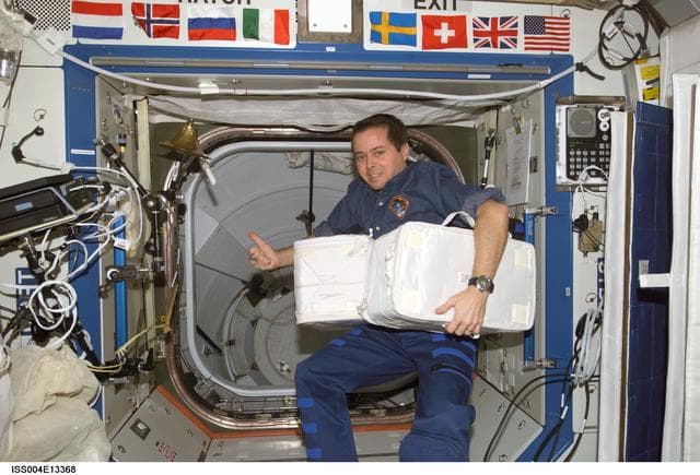 NASA image: Bursch transfers stowage containers during Expedition Four