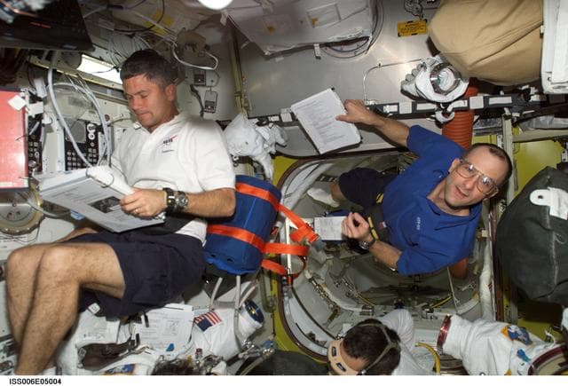 NASA image: STS-113 Pilot Lockhart and Expedition Six Flight Engineer Pettit are looking over a checklist in Airlock