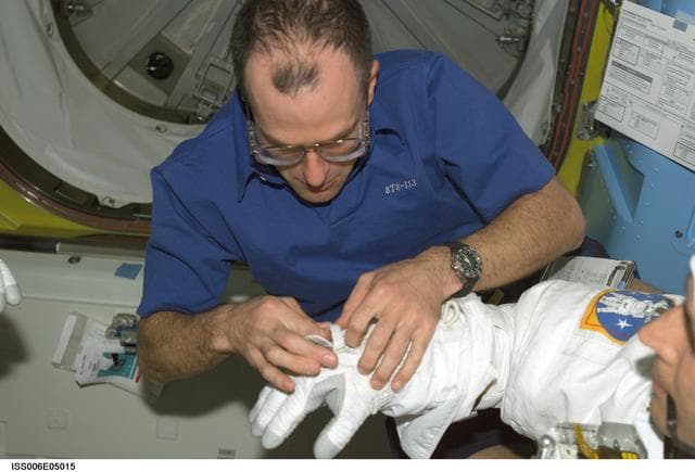 NASA image: Expedition Six Flight Engineer Pettit is assisting STS-113 MS Herrington with his EMU Spacesuit