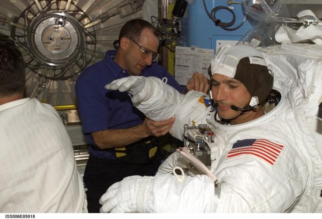 NASA image: Expedition Six Flight Engineer Pettit is assisting STS-113 MS Herrington with his EMU Spacesuit