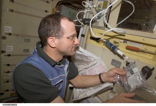 NASA image: Expedition Six Flight Engineer Pettit uses a chemical/microbial analysis bag to collect water sample