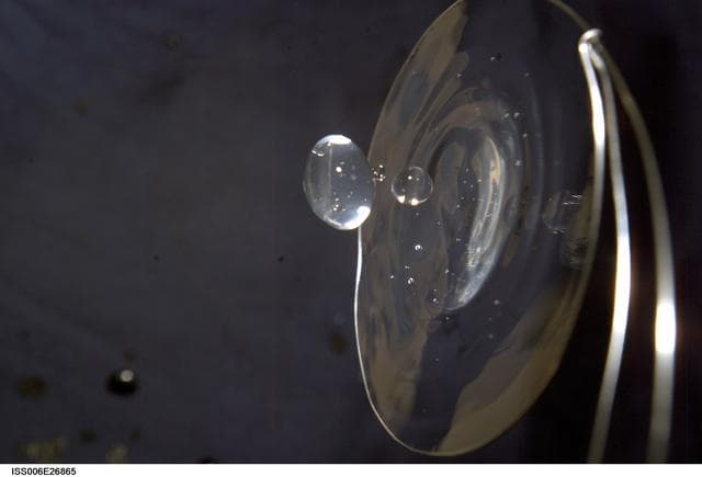 NASA image: View of a surface tension demonstration using water that is being held in place by a 50mm metal loop