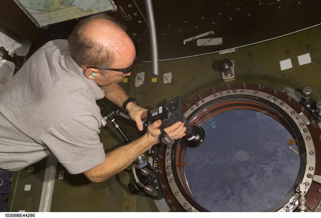 NASA image: Commander Kenneth D. Bowersox uses a camera to photography the earth from the nadir window