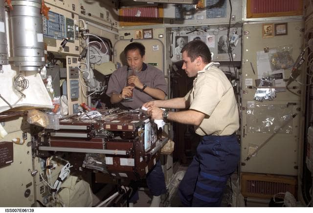 NASA image: Expedition Seven CDR Malenchenko and Science Officer Lu share meal in Zvezda