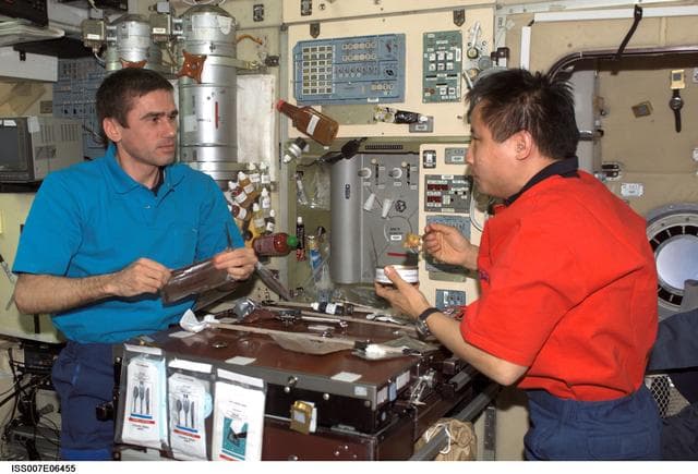 NASA image: Expedition Seven CDR Malenchenko and Science Officer Lu share meal in Zvezda