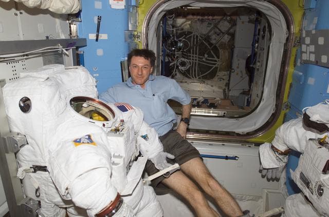 NASA image: Foale poses with a stowed EMU and EVA equipment in the Quest A/L during EXP 8