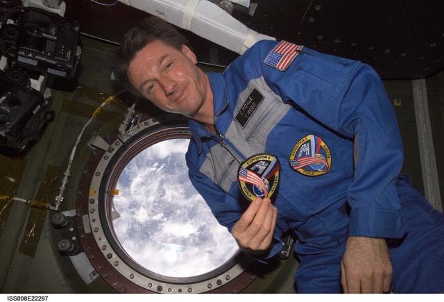 NASA image: Foale, holding EXP 8 patch, poses beside science window in the U.S. Lab