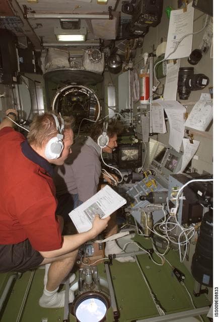 NASA image: Fincke reads a checklist as he watches Padalka at the Simvol-Ts workstation during Progress 14P docking approach OPS on Expedition 9