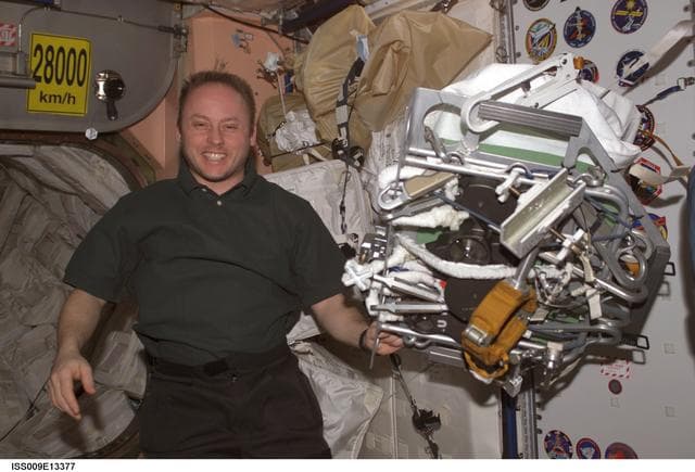 NASA image: Fincke poses with a packed EVA tool and gear bundle in Node 1 during Expedition 9