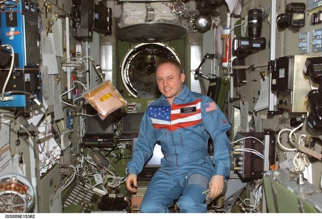 NASA image: Fincke stands beside a floating bag of tomato seeds for the EPO Tomatosphere II project during Expedition 9