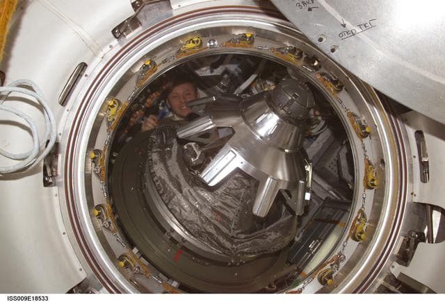 NASA image: Fincke inside the Progress Vehicle with open SM/Progress transfer hatch during Expedition 9