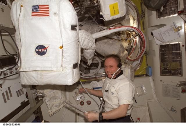 NASA image: Fincke performs EMU water sample and flushing operations in the A/L during Expedition 9