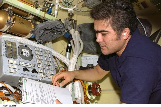 NASA image: Sharipov reads manual at the Russian Orlan Interface Unit in the Pirs DC1 during Expedition 10